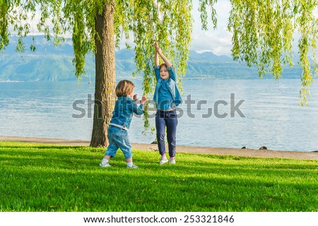 Two kids having fun outdoors on a nice sunny day, playing by the lake