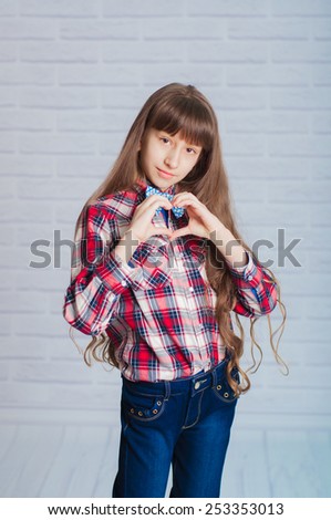 Little girl in jeans and a plaid shirt hands folded in the shape of heart