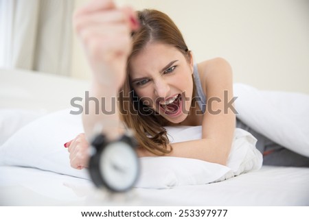 Angry woman who woke up very early to call an alarm clock in the bedroom