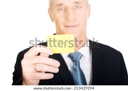 Mature businessman showing a yellow identity name card.