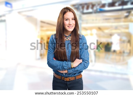 Trendy young woman looking happy with her arms crossed. Over shopping center background