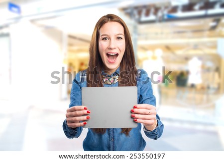 Trendy young woman looking surprised and holding a grey card. Over shopping center background