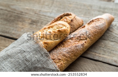 Three baguettes on the wooden background Royalty-Free Stock Photo #253552834