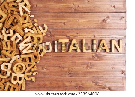 Word italian made with block wooden letters next to a pile of other letters over the wooden board surface composition