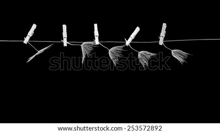 Dandelion seeds with small, wooden laundry nippers and thin metallic wire on black background 