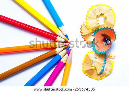 seven colored pencils and shavings on white background with copy space