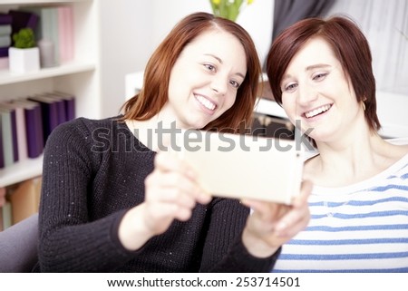 portrait of two happy young girls with smart phone at home