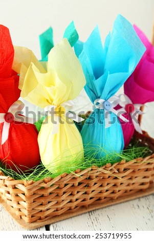 Easter eggs in basket on white wooden background