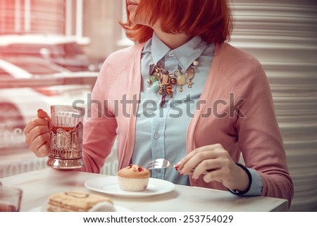beautiful young woman is having tee and cake in a nice cafe. Photos in purple tones