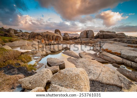 Long exposure photography of waves crashing over rocks at sunrise with storm clouds building