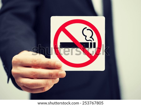 picture of man in suit holding no smoking sign