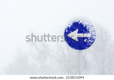 snowy one way obligatory direction traffic sign with blizzard