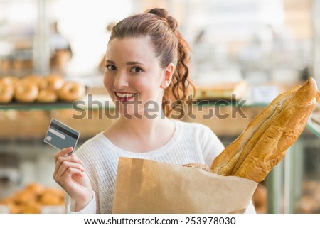 Pretty brunette with bag of bread and credit card at the bakery