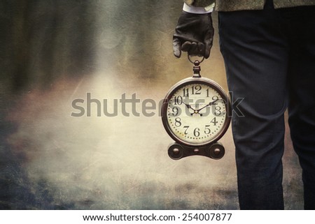 Vintage Background with man holding retro alarm clock in hand. Royalty-Free Stock Photo #254007877