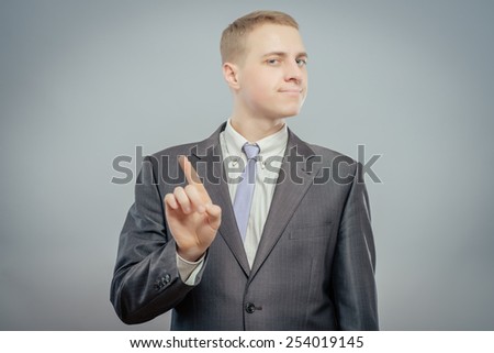 Closeup portrait of young business man pointing up having idea, solution, showing with index finger number one, isolated on gray background. Positive human emotions, facial expressions, symbols, sign