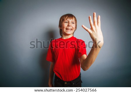 European-looking boy of ten years shows a figure four fingers on a gray background cross process