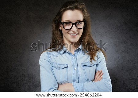 Cheerful young woman in jeans shirt and glasses