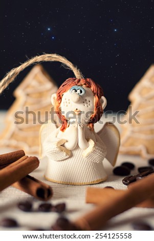 Prayer ceramic angel in fairy forest from gingerbread Christmas tree and cinnamon stick and coffee beans