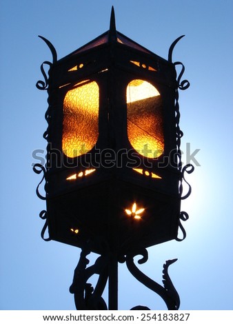 Decorative urban lamp with the sun behind  Royalty-Free Stock Photo #254183827