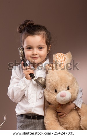Young girl with plosh toy calls to the hospital on a brown background.
