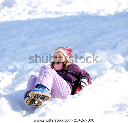 little girl plays with sledding on snow in the winter in the mountains