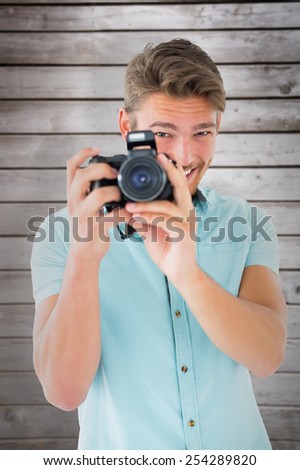 Handsome young man holding digital camera against wooden planks