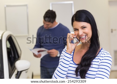 Smiling customer making a phone call at new car showroom