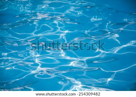 Swimming pool blue water surface with bright sun light reflections