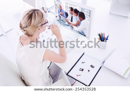 Female photo editor working on computer against group of business people brainstorming together