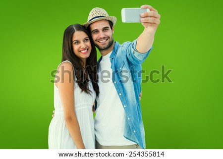 Happy hipster couple taking a selfie against green vignette