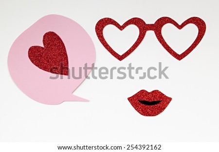 Pink speech bubble with red glitter heart, glasses and lips