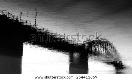 Old bridge reflection on water, artistic photo, black and white conversion.