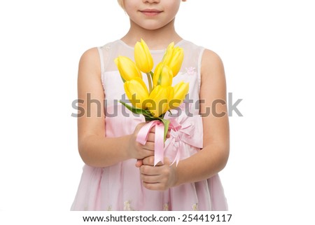 Close up picture of cute girl wearing pink dress, standing isolated on white background and holding nice bouquet of yellow tulips