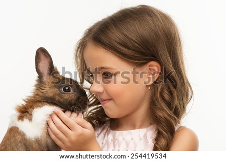 Close up photo of beautiful little girl looking at cute brown bunny, isolated on white background