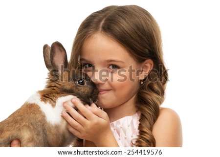 Close up photo of beautiful little girl kissing cute brown bunny, isolated on white background