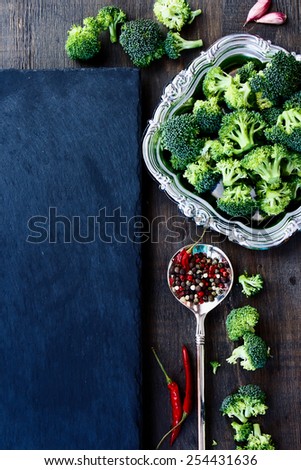 Food background with fresh green broccoli and spices. Slate and wood background with copyspace. Top view.