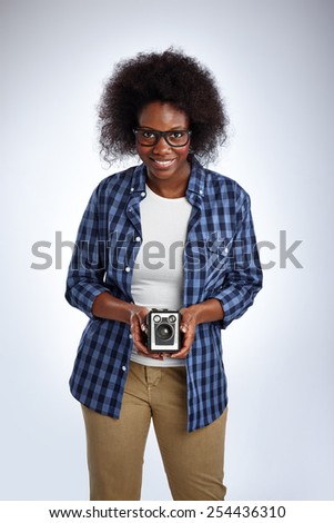 Mature african woman taking a picture with a vintage camera on white background