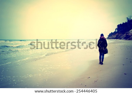 Emotion conceptual image. Lonely woman walking on the beach. Instagram vintage picture.