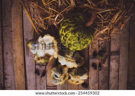 Sugar apple - cherimoya ( Annona scaly ) on the board with hay with bones and a plate