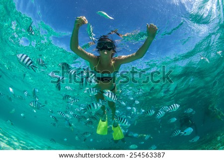 Beautiful girl with black hair has been snorkeling on the island of Mauritius in the Indian Ocean. She feeds the fish under water in clear turquoise water Royalty-Free Stock Photo #254563387
