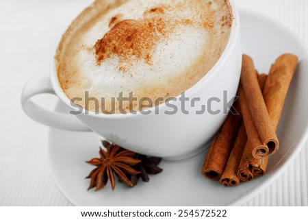 Cup of cappuccino and saucer on the table on a velvet drape, cinnamon and star anise