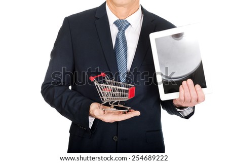 Close up businessman holding shopping cart and tablet.