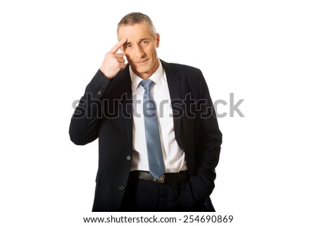 Mature businessman gesturing with finger against temple