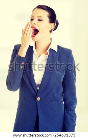Tired business woman in a suit yawning.