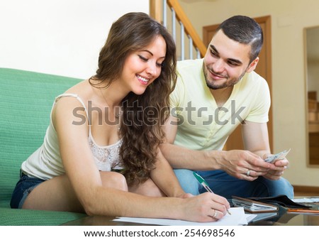 Smiling couple with money and financial documents  in home interior