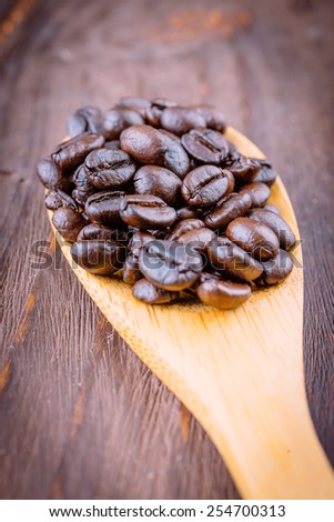 Coffee beans in wooden spoon on wood background - vintage effect style pictures
