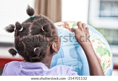 African girl in primary classroom playing with earthglobe.