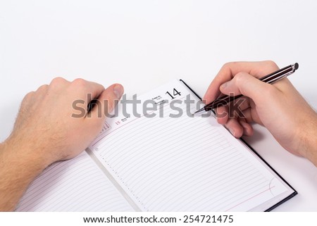 isolated hand holding pen and writing in diary