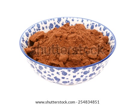 Cocoa powder in a blue and white porcelain bowl with a floral design, isolated on a white background