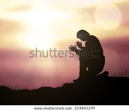 Easter Sunday concept: Lonely man kneeling and praying to Jesus Christ over blurred nature sunset background